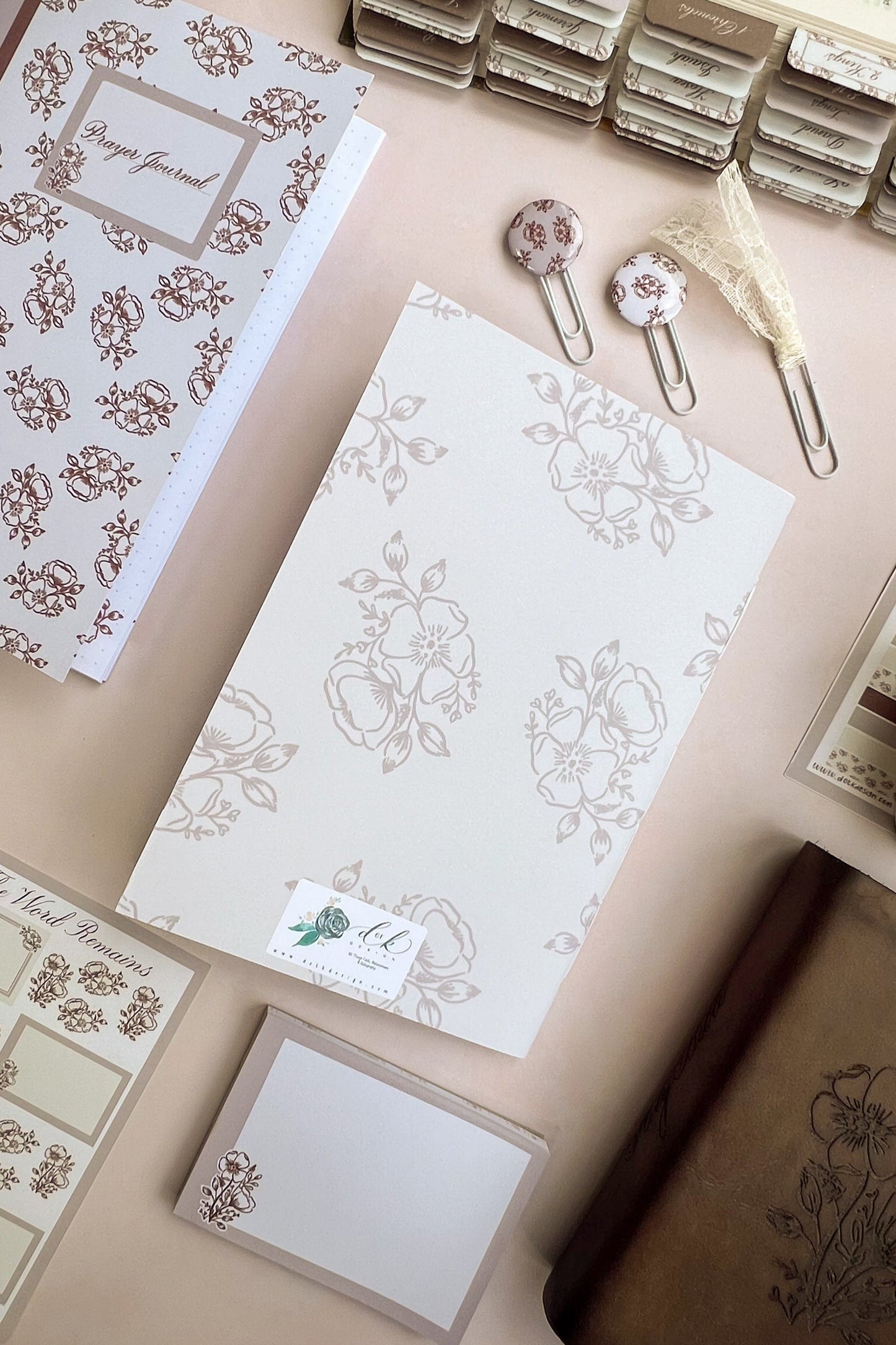 The back cover of a Sepia toned Christian prayer journal notebook featuring a floral design & Hand-lettering inspired by Isaiah 40:8 on the cover.