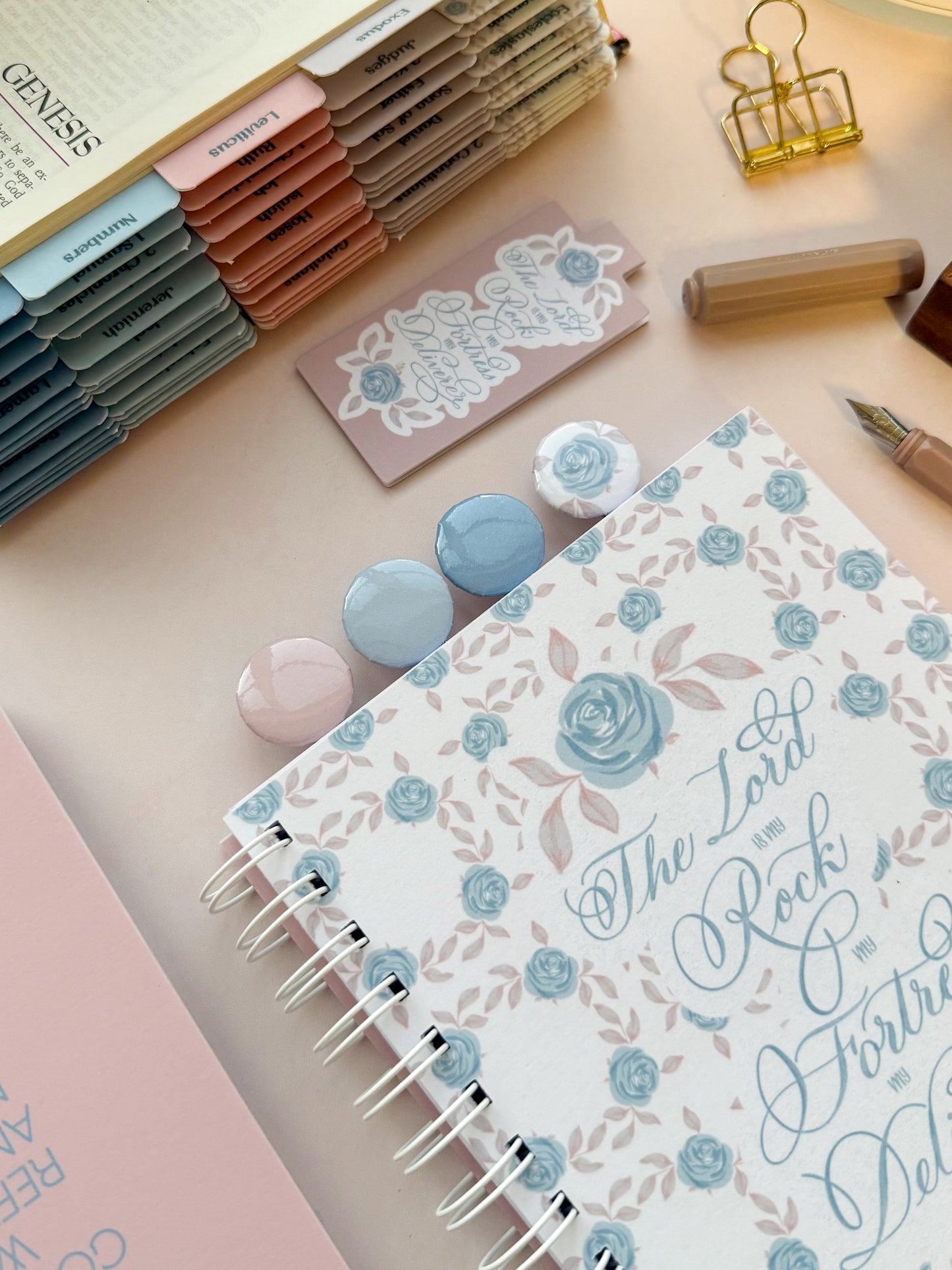 DotK Design Paperclip bookmarks being used in a journal. Each features shades of blue and pink with florals