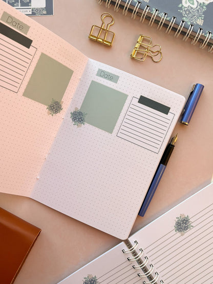 Open Christian prayer journal notebook featuring Dot grid pages with sections and blue floral accents at the base of each page.