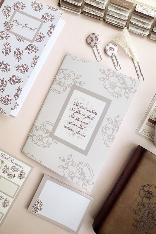Sepia toned Christian prayer journal notebook featuring a floral design & Hand-lettering inspired by Isaiah 40:8 on the cover.